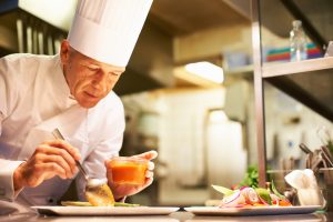 Portrait of smart chef preparing delicious meal for customer